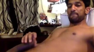 Ek banda, nude hoke apne cock ke saath hilate hue, cam show pe baitha hai.